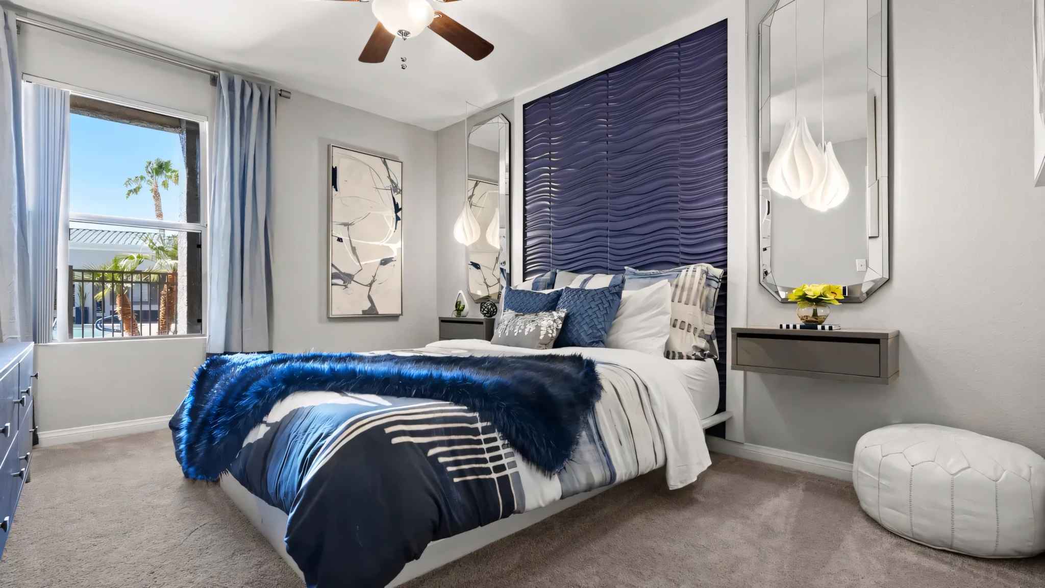 bedroom with bed decorative wall with mirror window showing view of pool and ceiling fan at Millennium East
