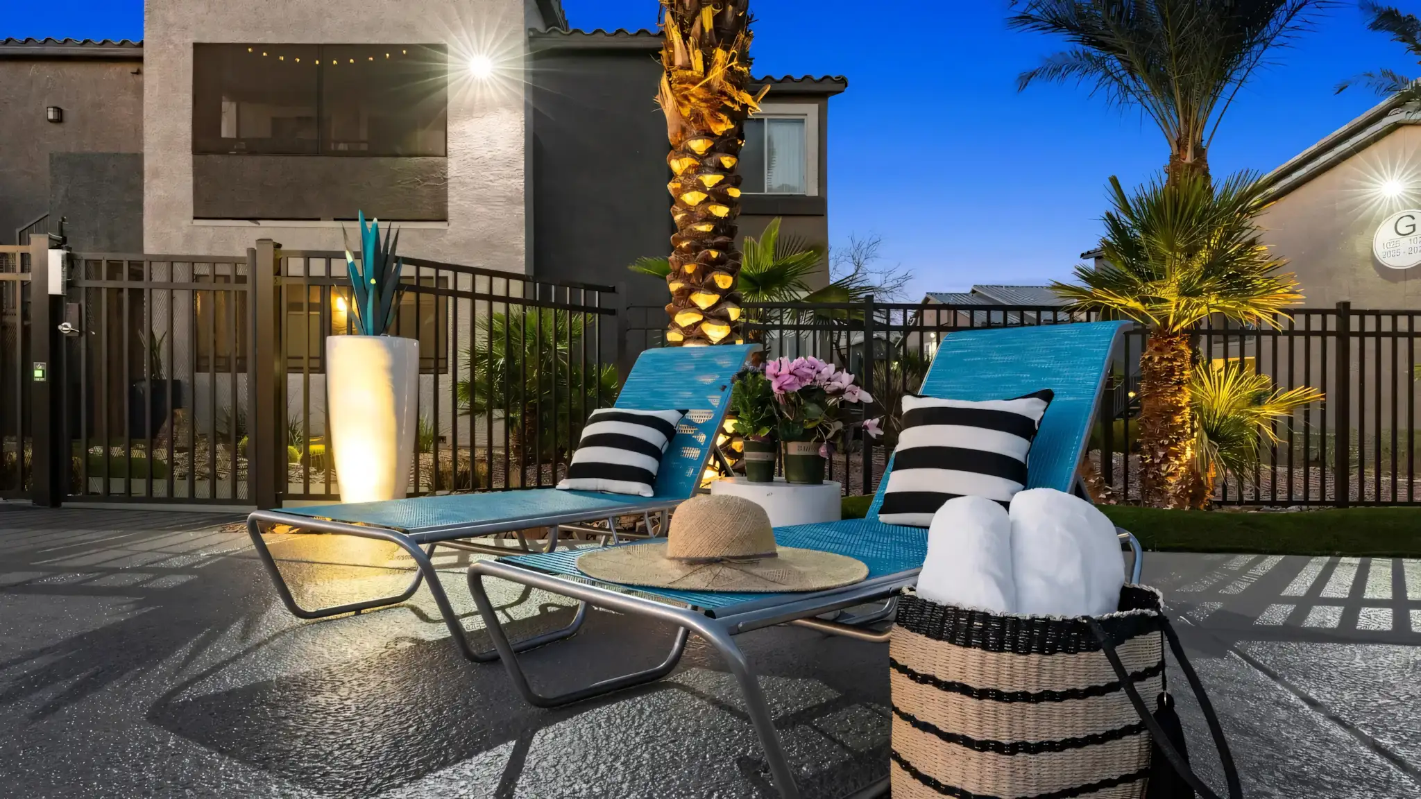 Millennium East Apartments close up evening view of two pool loungers under a palm tree