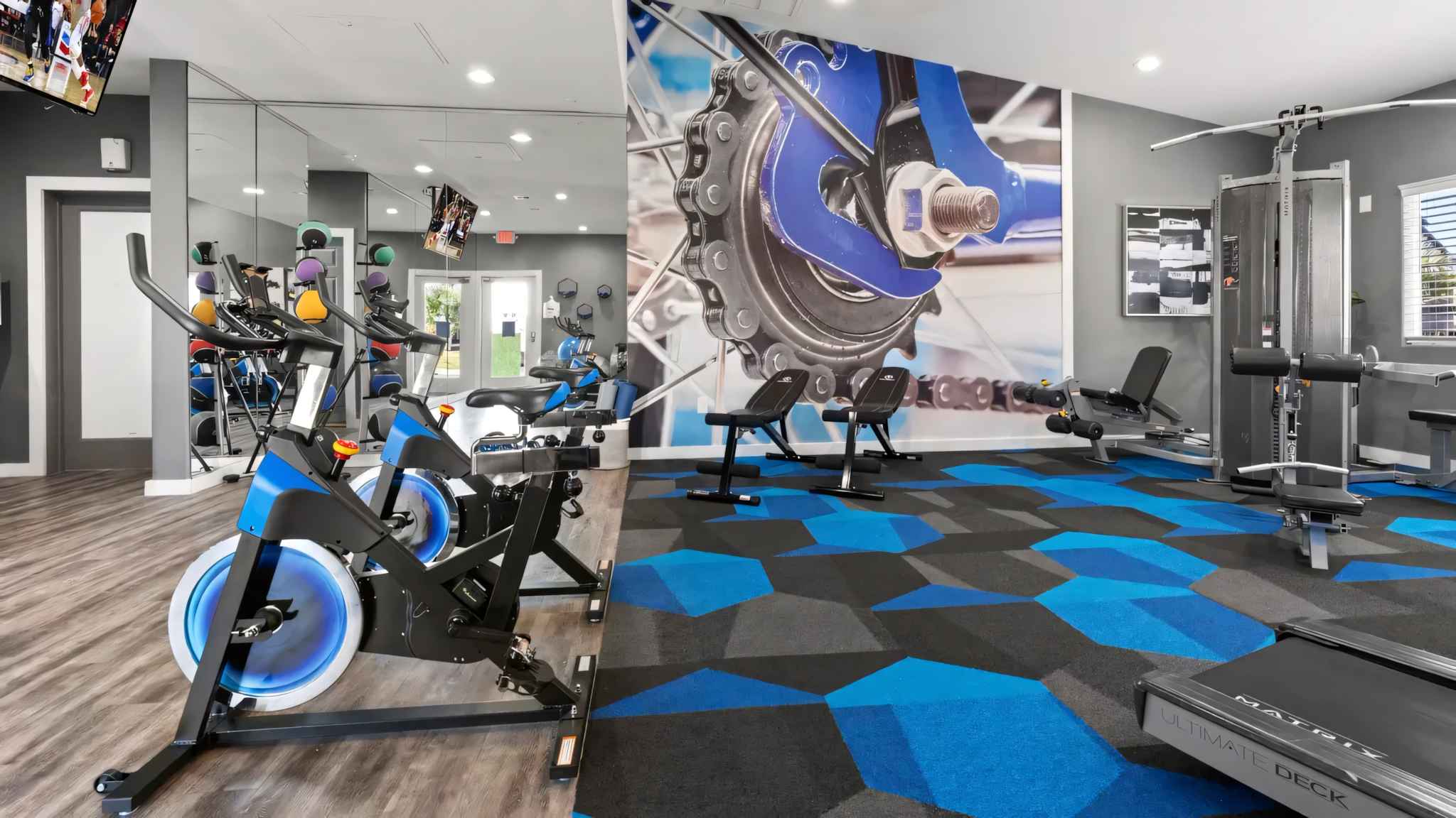 fitness center spilt view left side showing bicyles and right side lifting machine and benches at Millennium East